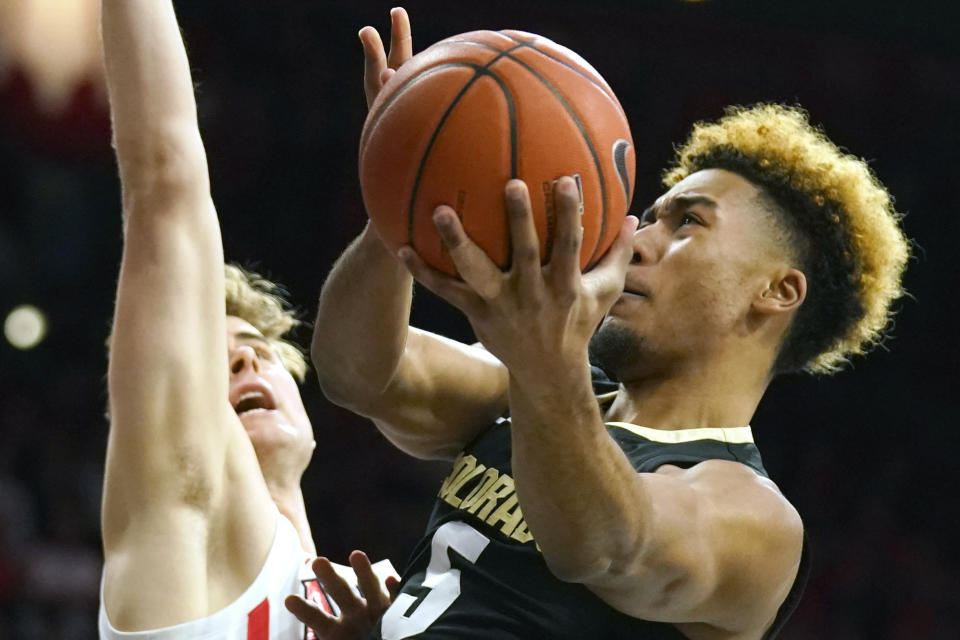 Colorado guard D'Shawn Schwartz (5) drives past Arizona forward Stone Gettings during the first half of an NCAA college basketball game Saturday, Jan. 18, 2020, in Tucson, Ariz. (AP Photo/Rick Scuteri)