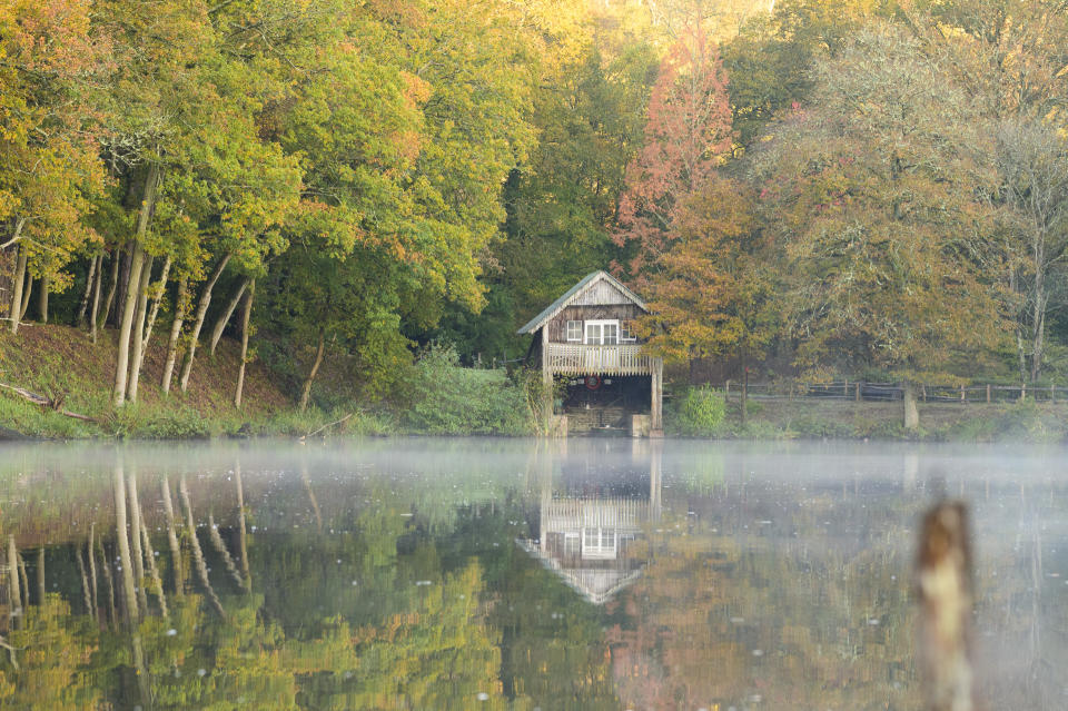 Boathouse in autumn reflected in a lake