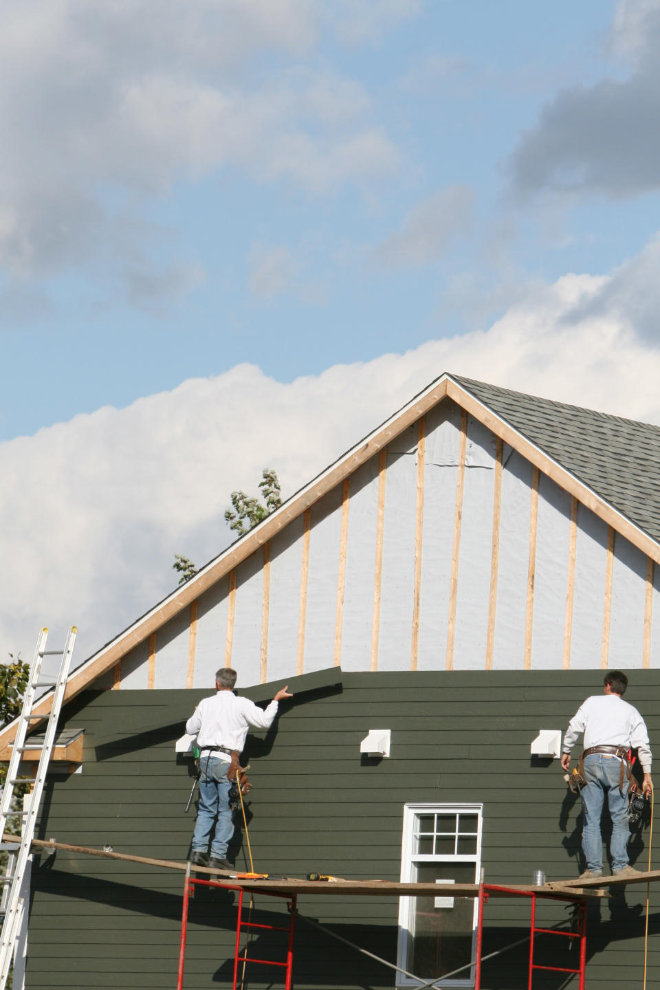 people fixing the siding of a home