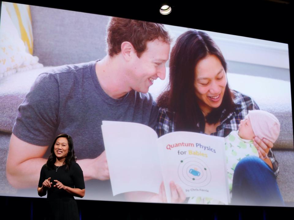 Priscilla Chan stands on stage in front of photo of her, Mark Zuckerberg, and their daughter Max