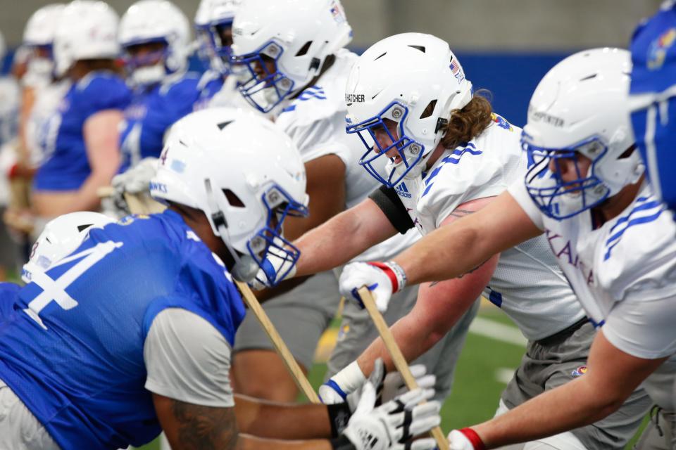 Kansas offensive and defensive linemen work with wooden boards during Tuesday's practice inside Kansas' indoor practice facility.