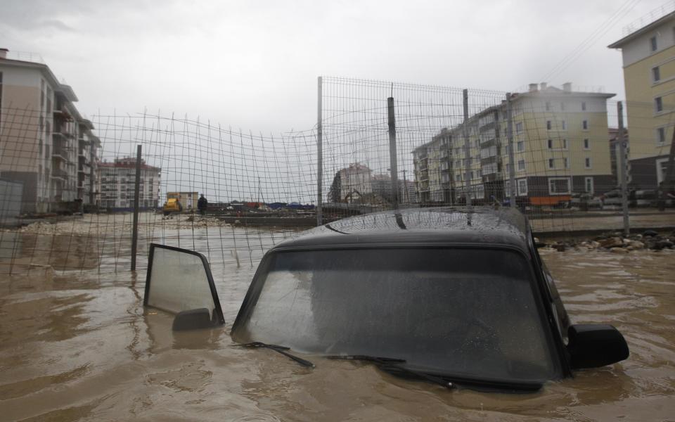 Car stranded in floodwaters is seen on a flooded street in Sochi