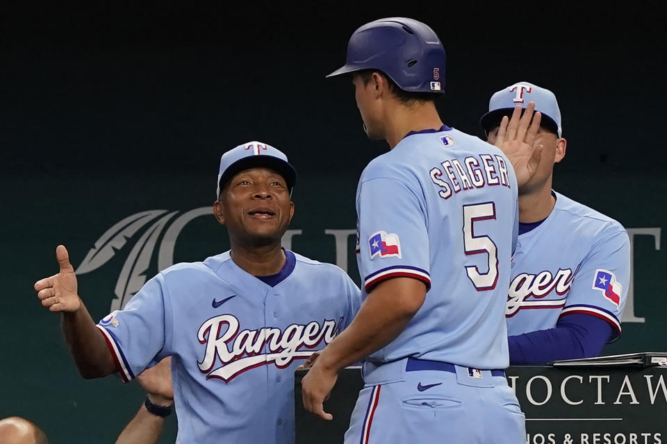 Texas Rangers interim manager Tony Beasley, left, congratulates Corey Seager (5) after Seager scored on single by Nathaniel Lowe during the first inning of a baseball game against the Toronto Blue Jays in Arlington, Texas, Sunday, Sept. 11, 2022. (AP Photo/LM Otero)