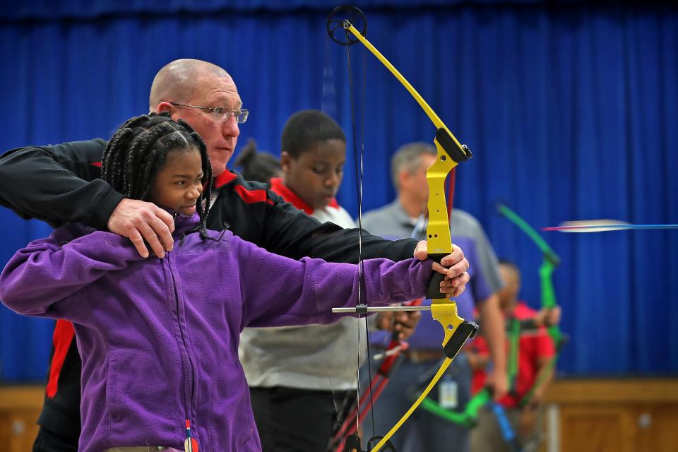 William Crawford helps Brianna Smith shoot during archery class at Lew Wallace Elementary IPS 107, Thursday, Dec. 20, 2018.