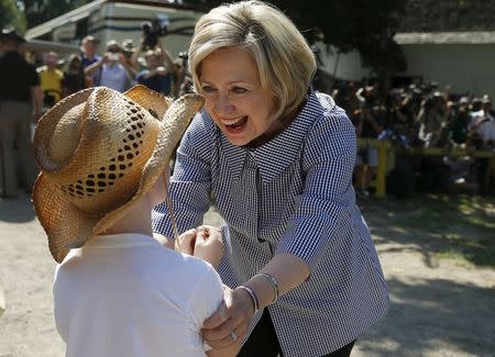 U.S. Democratic presidential candidate Hillary Clinton greets Louie Dixon as she campaigns at the Iowa State Fair in Des Moines, Iowa, United States, August 15, 2015. REUTERS/Jim Young