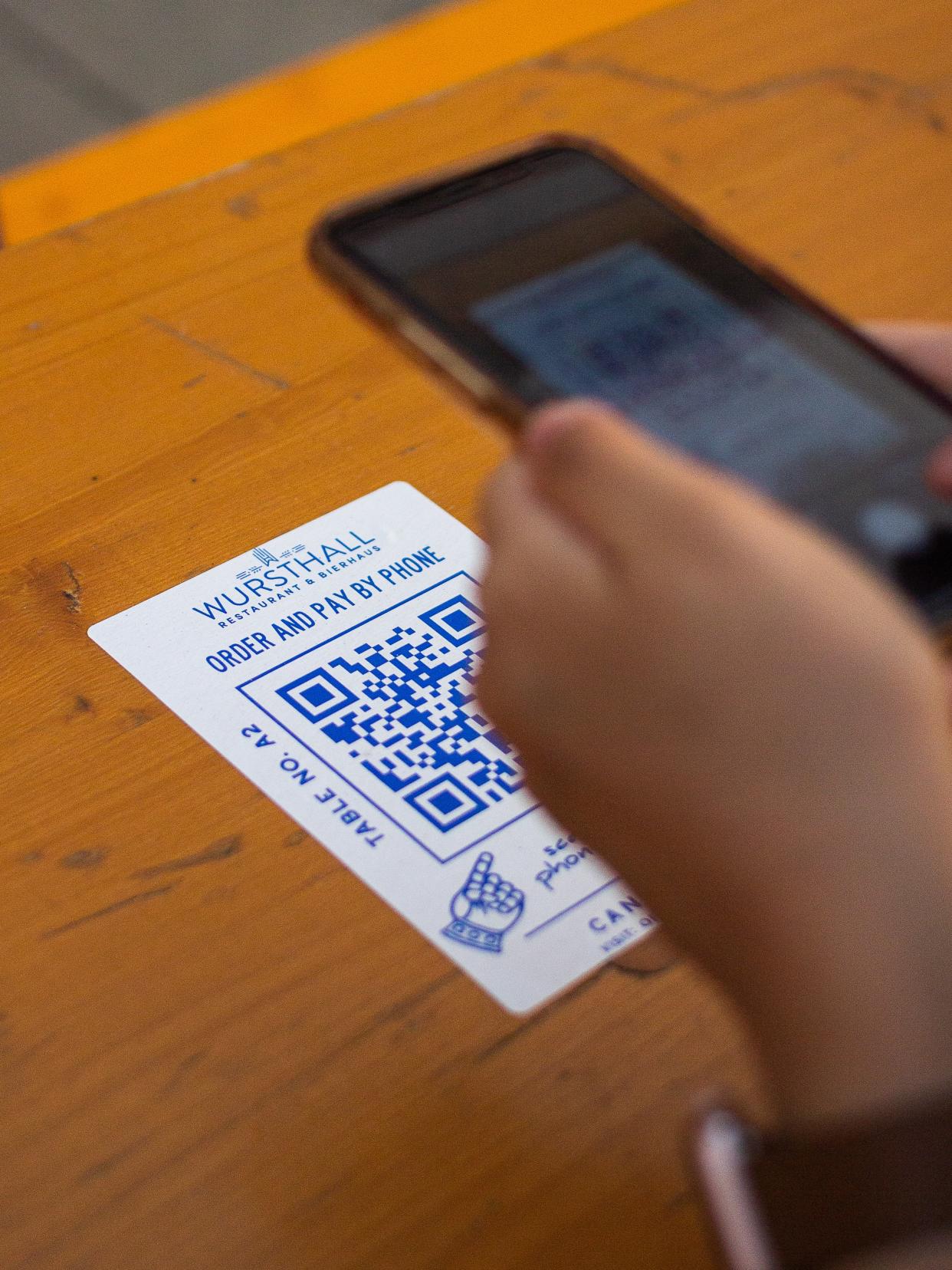  A person holding an iPhone over a QR code on a table. 