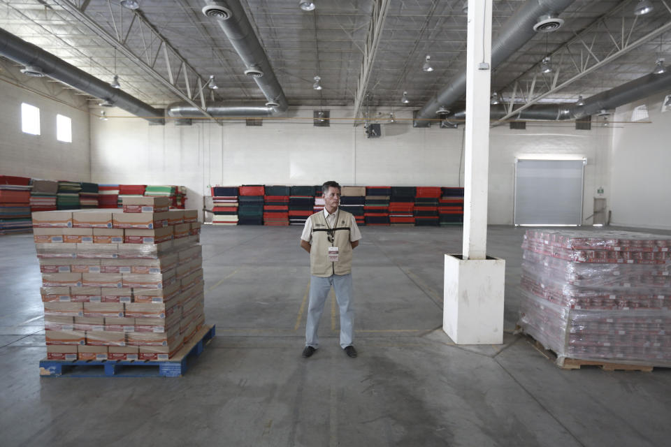 A Mexican government worker stands inside what was once an assembly plant and has been converted into a migrant shelter in Ciudad Juarez, Mexico, Thursday, Aug. 1, 2019. The Mexican government opened its first shelter here to house Central American and other migrants seeking asylum in the United States who have been sent back to Mexico to await the process. (AP Photo/Christian Chavez)