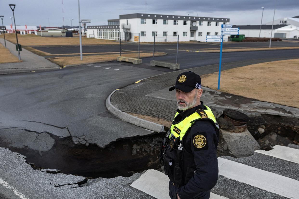 A police officer stands by the crack in a road in the fishing town of Grindavik (REUTERS)