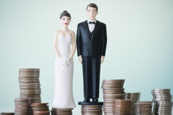 Close up of wedding cake figurines on stacks of coins