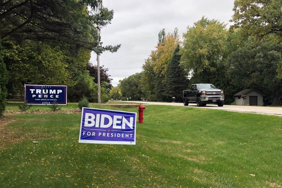Signs for Democratic presidential nominee former Vice President Joe Biden and President Donald Trump on adjacent lawns in a middle-class neighborhood of Oshkosh, the hub of swing-voting Winnebago County, Wis.