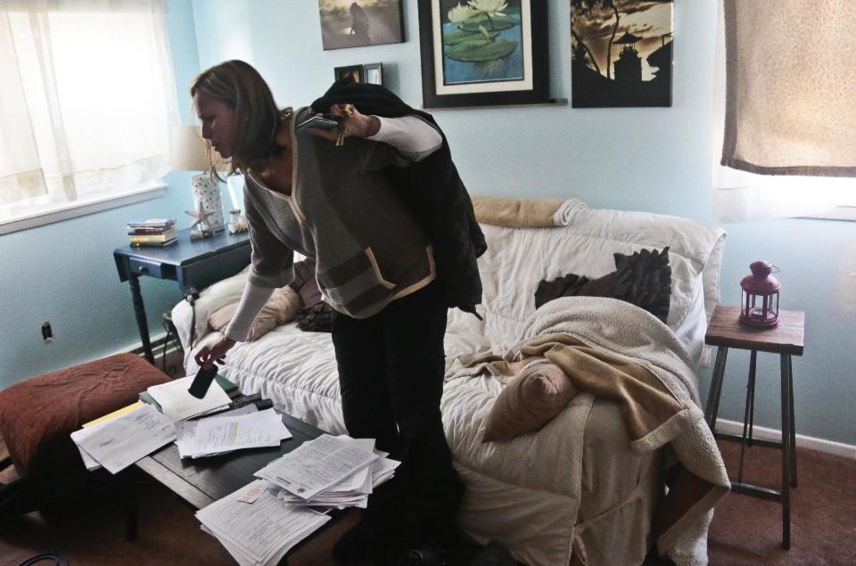 In this March 11, 2014 photo, Nora Milligan looks through a pile of legal healthcare documents at her home in Patchogue, NY. . Milligan, a single mom, is fighting healthcare providers in court for denial of care to her heroin-addicted son. Having exhausted her finances for his care, she continues to live in the home she raised him even as it is being foreclosed. (AP Photo/Bebeto Matthews)