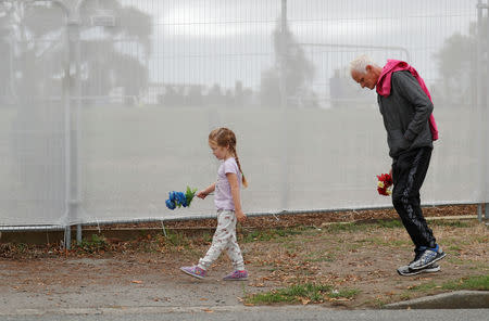 A man and a girl hold flowers and walk as people attend the burial ceremony for the victims of the mosque attacks at the Memorial Park Cemetery in Christchurch, New Zealand March 21, 2019. REUTERS/Jorge Silva