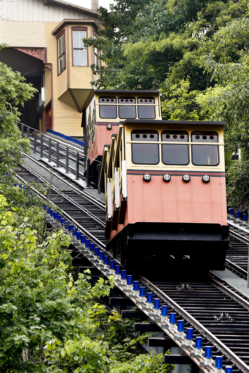 The cars for the Monongahela Incline pass on Friday, May 10, 2019, in Pittsburgh. The incline that transports people up and down the side of a hill in Pittsburgh reopened Friday after being closed since February. (AP Photo/Keith Srakocic)