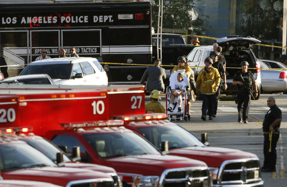 FILE - In this July 21, 2018, file photo, Los Angeles Police SWAT officers, and Los Angeles firemen wearing bulletproof helmets, evacuate a child, after a gunman barricaded himself inside a Trader Joe's store in Los Angeles. The family of a bystander accidentally killed by police when they tried to stop an armed man from entering a Los Angeles grocery store is blasting newly released video of the incident, saying it's crafted to paint officers in the best light. The Los Angeles Police Department released more footage of the July shooting Tuesday, Sept. 4, 2018. It includes about six minutes of footage from the 14-minute chase, the ensuing shootout with police, and hours-long standoff inside the grocery store. (AP Photo/Damian Dovarganes, File)