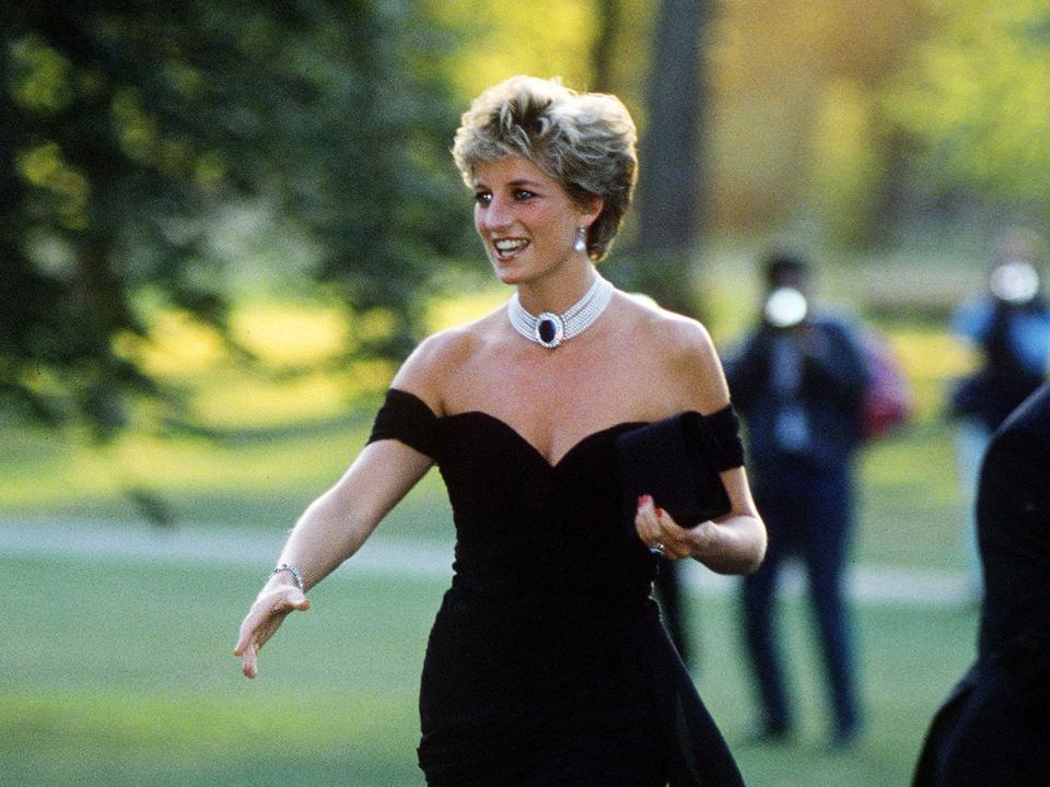 Princess Diana wears the "revenge dress" and stretches her hand out to greet someone