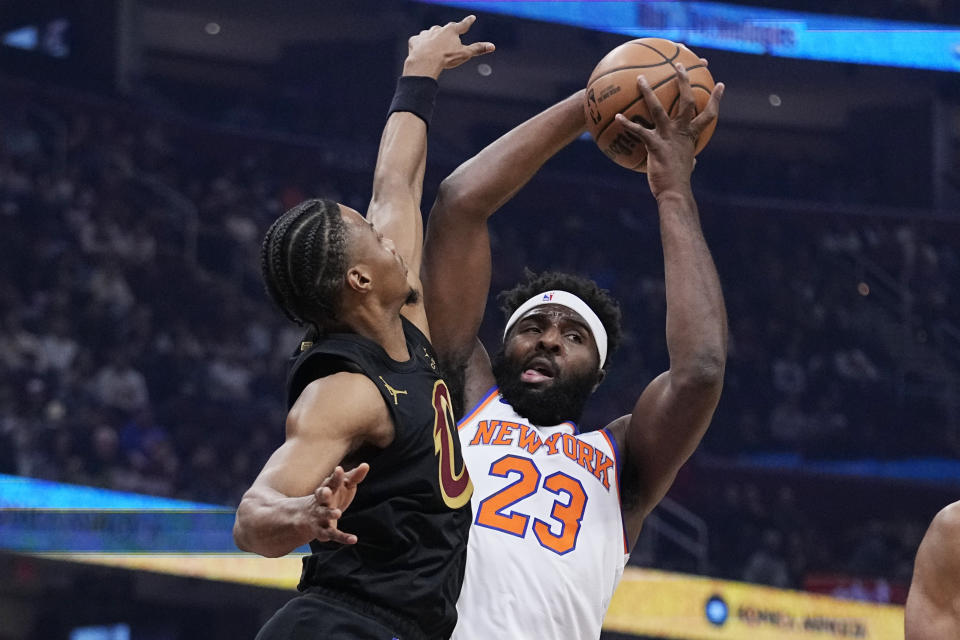 New York Knicks center Mitchell Robinson (23) grabs a rebound next to Cleveland Cavaliers forward Isaac Okoro during the first half of an NBA basketball game Tuesday, Oct. 31, 2023, in Cleveland. (AP Photo/Sue Ogrocki)