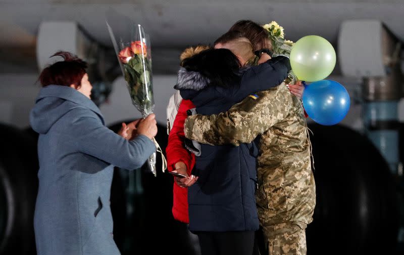 Relatives embrace a Ukrainian serviceman exchanged during a prisoners of war swap at an airport outside Kiev