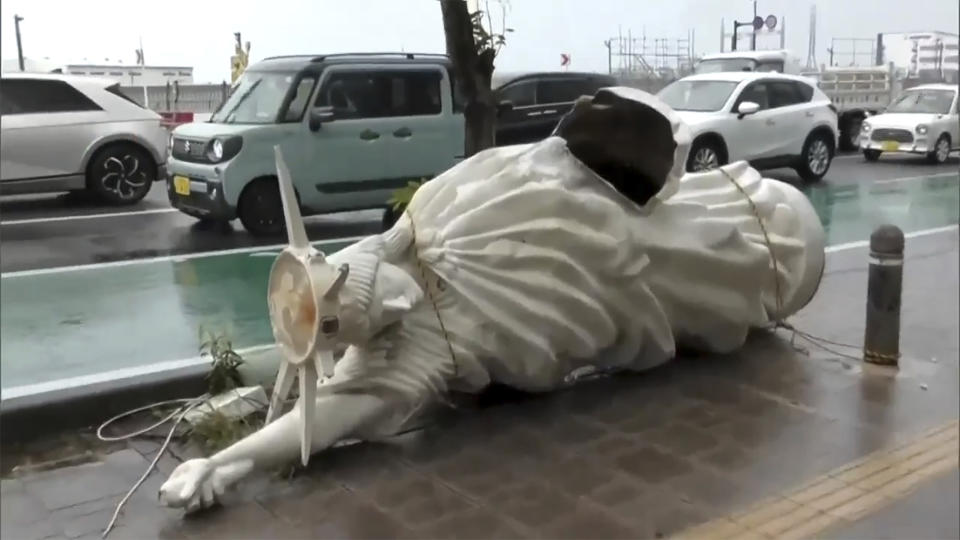 This image made from video provided by NTV shows a damaged statue lying on the street, following Typhoon Khanun, in Naha, Okinawa prefecture, Thursday, Aug. 3, 2023. The typhoon that damaged homes and knocked out power on Okinawa and other southern Japanese islands this week was slowly moving west Thursday but is forecast to make a U-turn and dump even more rain on the archipelago. (NTV via AP)