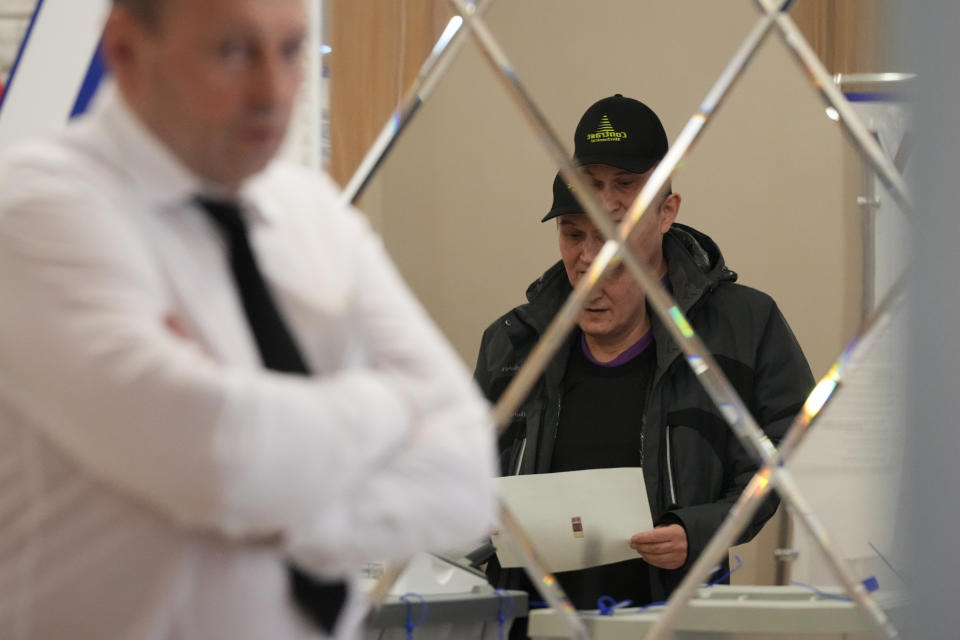 A man is reflected in a mirror as he casts a ballot at a polling station during the presidential elections in St. Petersburg, Russia, Saturday, March 16, 2024. Voters in Russia are heading to the polls for a presidential election that is all but certain to extend President Vladimir Putin's rule after he clamped down on dissent. (AP Photo/Dmitri Lovetsky)