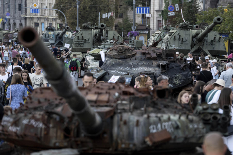 People walk in front of destroyed Russian tanks installed on Khreschatyk street in downtown of Kyiv, Ukraine, Saturday, Aug. 26, 2023. (AP Photo/Evgeniy Maloletka)