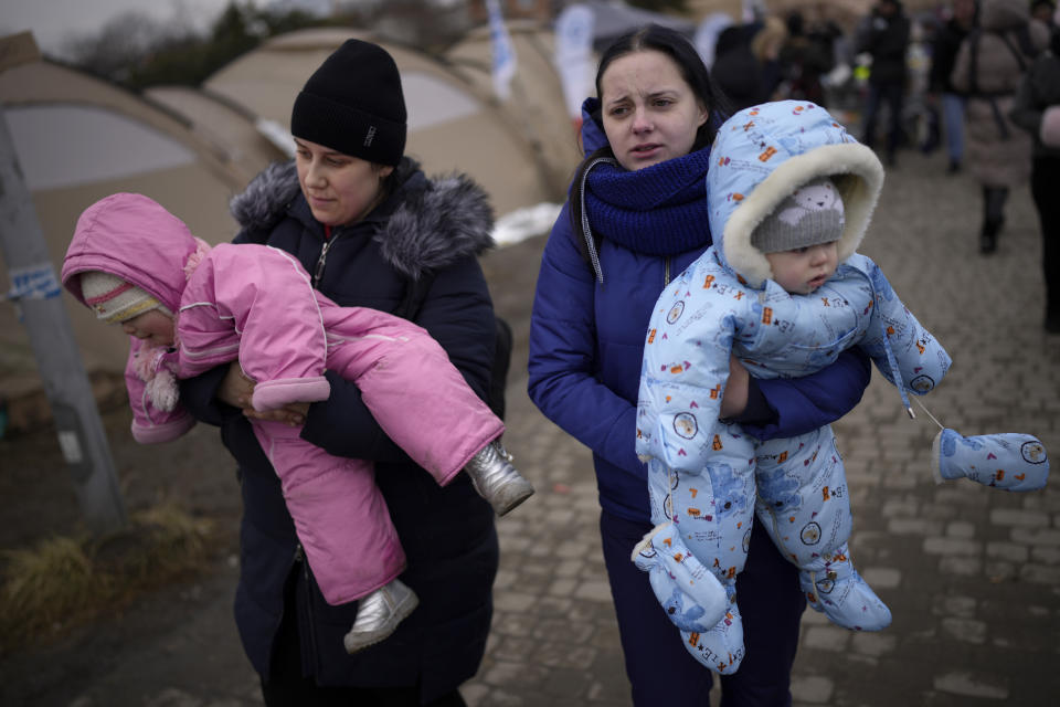 Women carry children after crossing from Ukraine in Medyka, Poland, Wednesday, March 9, 2022. (AP Photo/Daniel Cole)