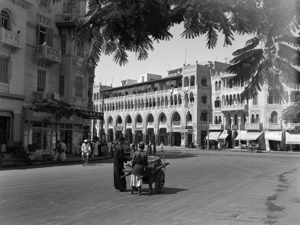 1920s 1930s STREET SCENE ARCHITECTURE IN ARAB STYLE VENDER PUSHING CART SUBURB OF CAIRO HELIOPOLIS EGYPT