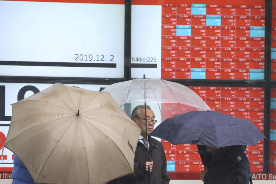 People walk by an electronic stock board of a securities firm in Tokyo, Monday, Dec. 2, 2019. Asian stock markets have risen after Chinese factory activity improved ahead of a possible U.S. tariff hike on Chinese imports. Benchmarks in Shanghai, Tokyo and Hong Kong advanced. (AP Photo/Koji Sasahara)