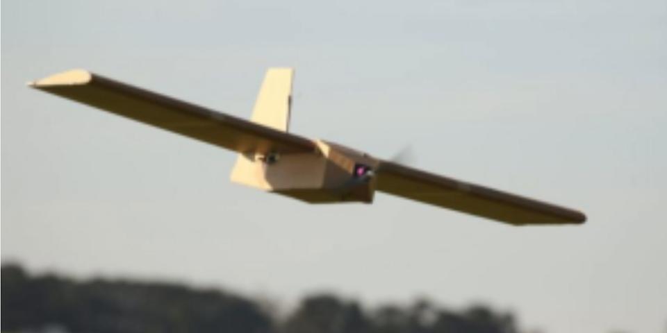 A drone, made from a lightweight material that resembles carboard, in the air