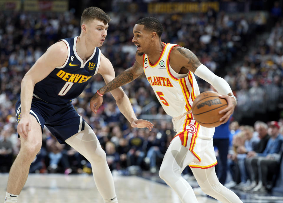 Atlanta Hawks guard Dejounte Murray, right, drives past Denver Nuggets guard Christian Braun in the first half of an NBA basketball game Saturday, Feb. 4, 2023, in Denver. (AP Photo/David Zalubowski)