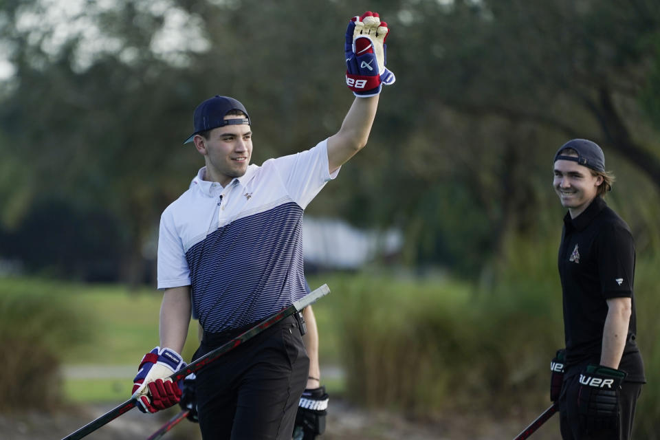 Nick Suzuki of the Montreal Canadiens, raises his hand after winning the golf skills competition, Wednesday, Feb. 1, 2023, in Plantation, Fla. The event was part of the NHL All Star weekend. To the right is Arizona Coyotes forward Clayton Kellar. (AP Photo/Marta Lavandier)