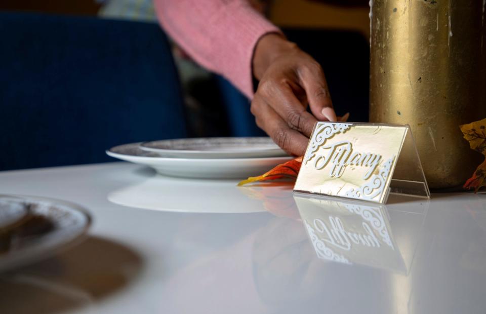 Tiffany Willis, the founder of The Wifestyle Academy, places a card with her name on her dining table inside her home in Southfield on Oct. 12, 2022. 