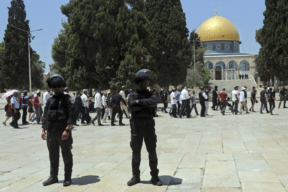 Israeli police officers stand guard as Jewish men visit the Dome of the Rock Mosque in the Al Aqsa Mosque compound, during the annual mourning ritual of Tisha B'Av (the ninth of Av) -- a day of fasting and a memorial day, commemorating the destruction of ancient Jerusalem temples, in the Old City of Jerusalem, Sunday, July 18, 2021. (AP Photo/Mahmoud Illean)