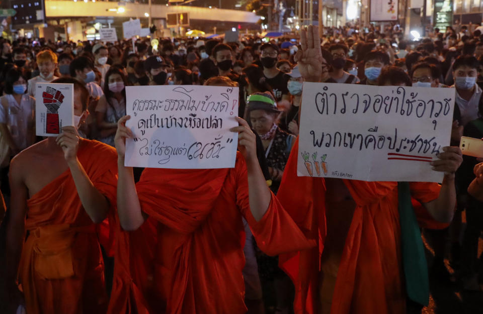 Buddhist monks supporters of pro-democracy protesters display placards as they march to the German Embassy in central Bangkok, Thailand Monday, Oct. 26, 2020. As lawmakers debated in a special session in Parliament that was called to address political tensions, the students-led rallies were set to continue with a march through centeral Bangkok Monday evening to the German Embassy, apparently to bring attention to the time King Maha Vajiralongkprn spends in Germany. Placards from left read: "Do you ever watch Dharma program? Or you watch only Nation channel, Police, do not use any weapon, because they are the people." (AP Photo/Gemunu Amarasinghe)