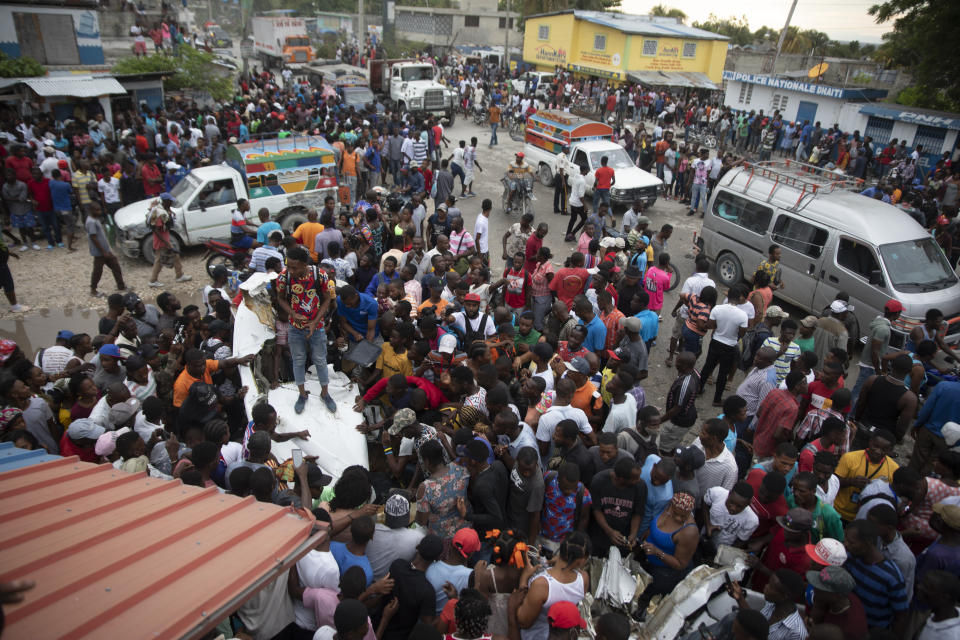 Onlookers mill around the wreckage of a small plane that crashed in the community of Carrefour, Port-au-Prince, Haiti, Wednesday, April 20, 2022. Police report that the plane was headed to the southern coastal city of Jacmel when it tried to land in Carrefour, and that at least 5 people died in the accident. (AP Photo/Odelyn Joseph)