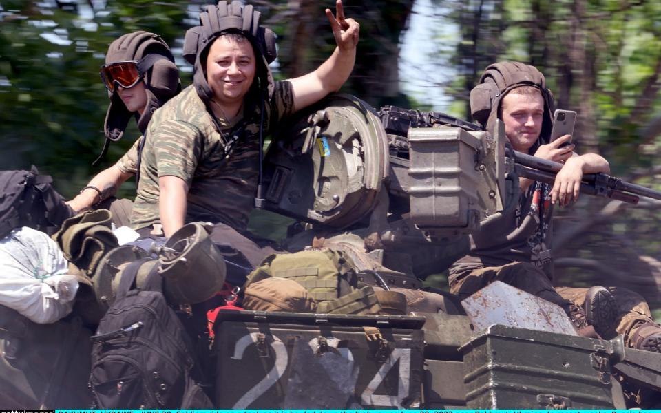 Soldiers ride on a tank as it is hauled down the highway on June 20 near Bakhmut, Ukraine  - Scott Olson/Getty Images