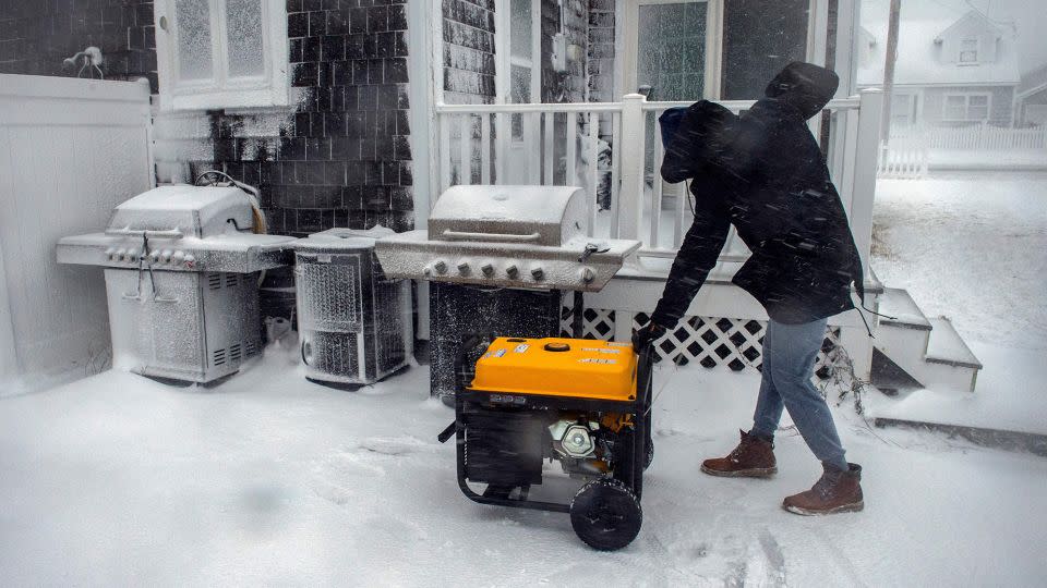 A man starts a generator at his home after losing power during a snow storm in Marshfield, Massachusetts, on January 29, 2022. - Joseph Prezioso/AFP/Getty Images