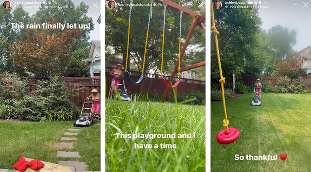 Ashley mowing the lawn in her backyard around a swing set and a stone path.