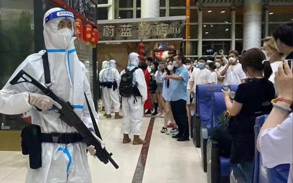 People confront armed guards in full hazmat suits as an entire airport is locked down