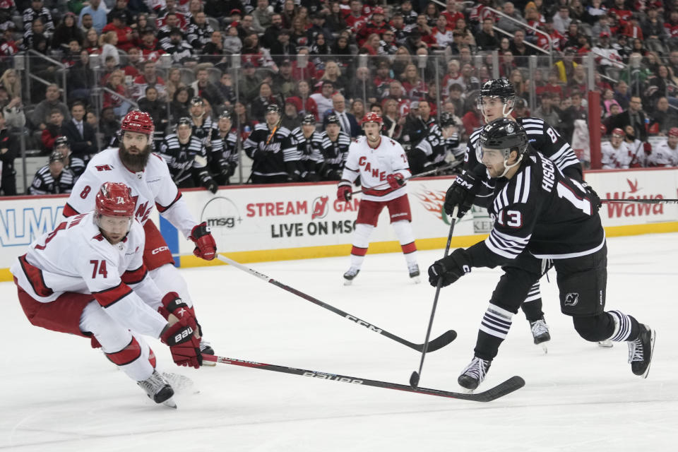 New Jersey Devils center Nico Hischier (13) shoots the puck to score past Carolina Hurricanes defenseman Jaccob Slavin (74) during the second period of an NHL hockey game, Saturday, March 9, 2024, in Newark, N.J. (AP Photo/Mary Altaffer)