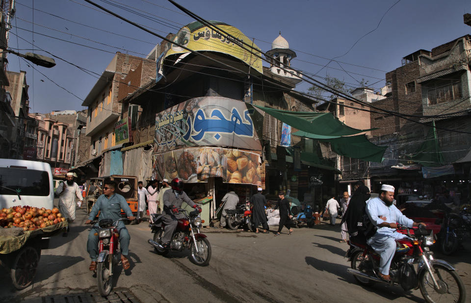 People and motorcyclists drive through Qissa Khwani market in the downtown of Peshawar, the capital of Pakistan's northwest Khyber Pakhtunkhwa province bordering Afghanistan, Friday, Oct. 8, 2021. Wahab, the youngest son of four from a wealthy Pakistani family was rescued by his uncle, from a Taliban training camp on Pakistan’s border with Afghanistan earlier this year. His uncle blamed his slide to radicalization on the neighborhood teens Wahab socialized with in their northwest Pakistan hometown, plus video games and Internet sites his friends introduced to him. (AP Photo/Muhammad Sajjad)