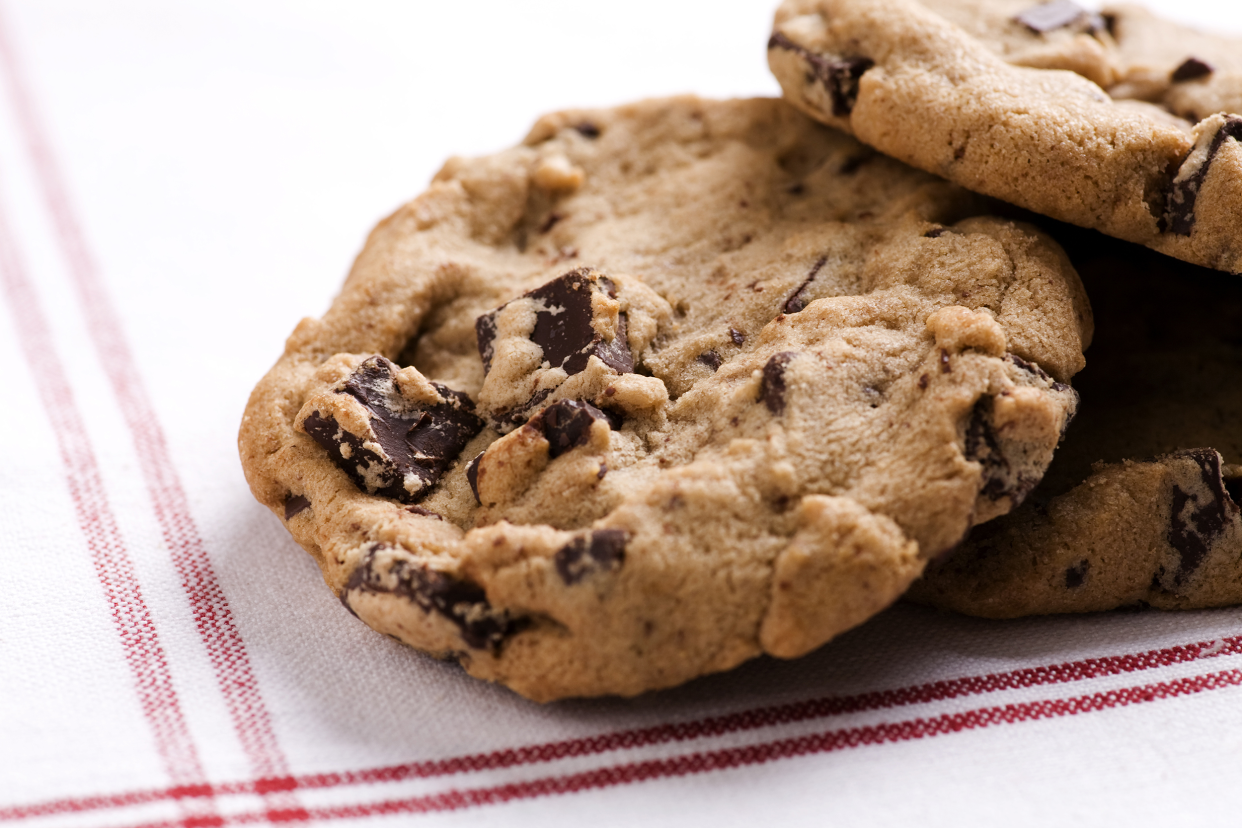 Closeup of a pile of three espresso chocolate chip cookies on a red-lined white napkin