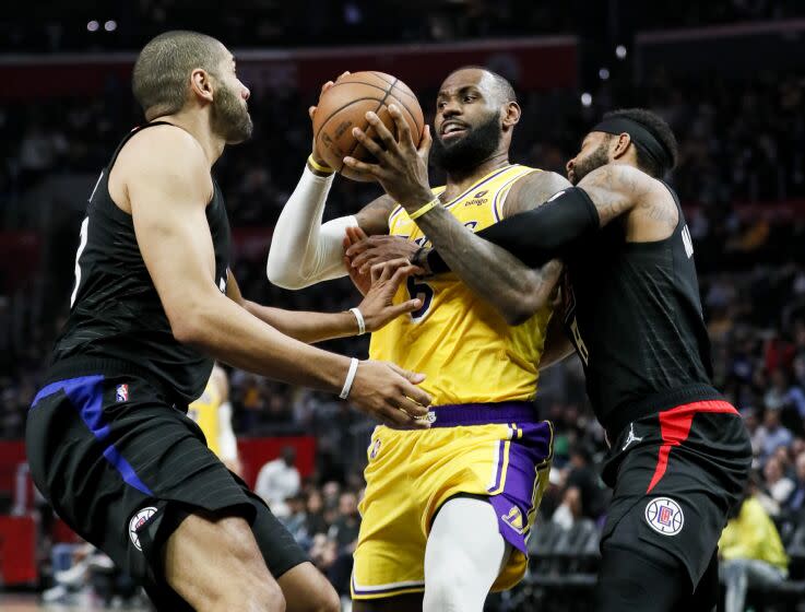 Los Angeles, CA - March 03: Los Angeles Lakers forward LeBron James (6) is tangled up by LA Clippers forward Marcus Morris Sr. (8) while driving to the basket in front of LA Clippers forward Nicolas Batum (33) during the second half at Crypto.com on Thursday, March 3, 2022 in Los Angeles, CA.(Robert Gauthier / Los Angeles Times)