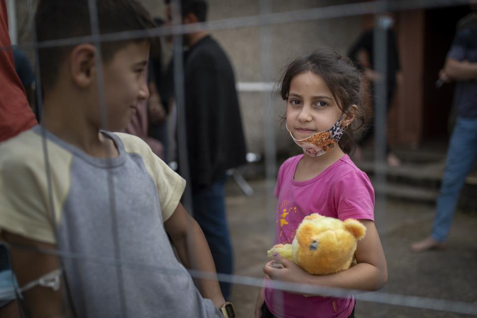 Girl, a migrant from Iraq, looks through a fence at the refugee camp in the village of Verebiejai, some 145km (99,1 miles) south from Vilnius, Lithuania, Sunday, July 11, 2021. Migrants at the school in the village of Verebiejai, about 140 kilometers (87 miles) from Vilnius, haven't been allowed to leave the premises and are under close police surveillance. Some have tested positive for COVID-19 and have been isolated in the building. (AP Photo/Mindaugas Kulbis)