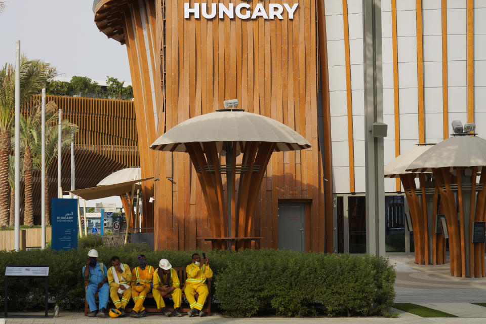 Workers take a break near the Hungary pavilion at Expo 2020 in Dubai, United Arab Emirates, Sunday, Oct. 3, 2021. Dubai's Expo 2020 on Saturday, Oct. 2, 2021, offered conflicting figures for how many workers had been killed on site during construction of the massive world's fair, first saying five and then later three. In a later statement, Expo apologized and described the initial figure as a "mistake." (AP Photo/Jon Gambrell)