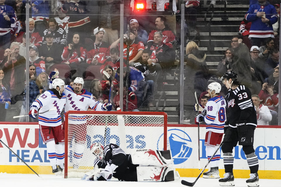 New York Rangers' Chris Kreider, center, celebrates with teammate Mika Zibanejad, left, after scoring a goal, as New Jersey Devils goaltender Vitek Vanecek, center, and Ryan Graves, right, react during the second period of an NHL hockey game Thursday, March 30, 2023, in Newark, N.J. (AP Photo/Frank Franklin II)