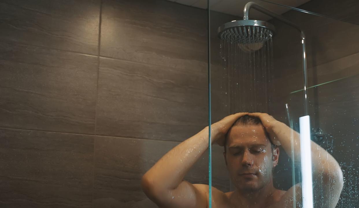 Man washes his hair in the shower at home.