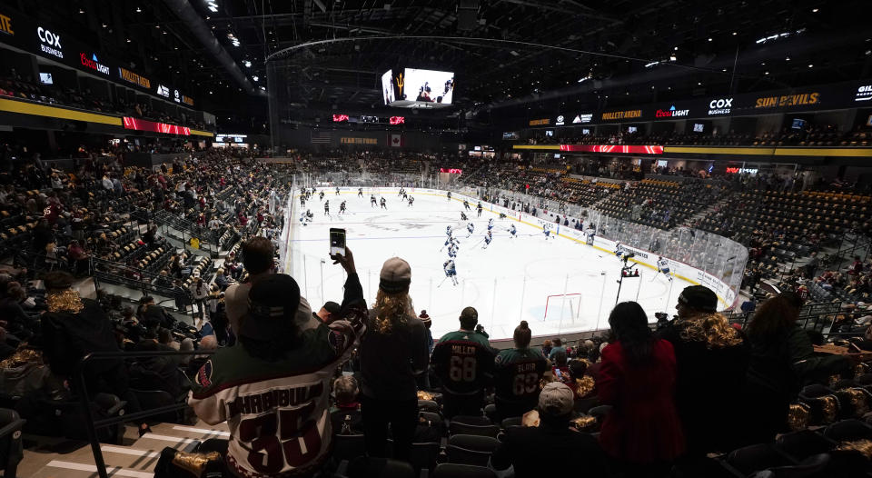 FILE - Fans watch as players warm up prior to the Arizona Coyotes' home-opening NHL hockey game against the Winnipeg Jets at the 5,000-seat Mullett Arena in Tempe, Ariz., Oct. 28, 2022. The Coyotes are about to learn the fate of a proposed entertainment district that will include a new arena. A referendum going before voters in the city of Tempe will determine whether plans for the $2.3 billion Tempe Entertainment District will move forward. (AP Photo/Ross D. Franklin, File)