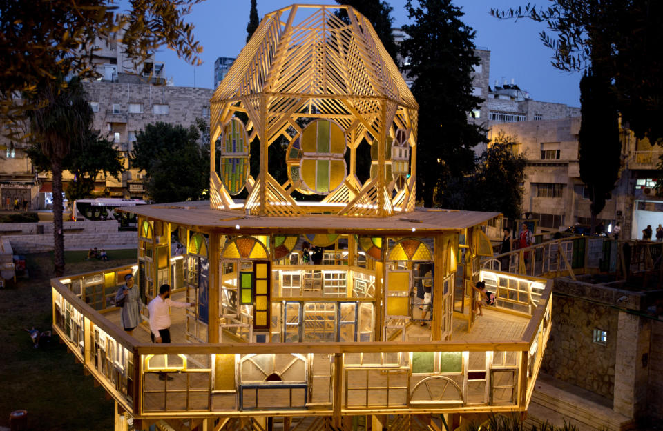 In this Tuesday, July 16, 2019 photo, people visit an art installation in Jerusalem. The project in downtown Jerusalem is using a tower of old windows to give a view of the city’s diverse cultural past and present and bring life to a neglected area. “Window Stories” is made of 500 windows collected by the late Jerusalem artist Yoram Amir, who organizers said was “madly in love” with the city and its many ethnic and religious communities. (AP Photo/Dusan Vranic)