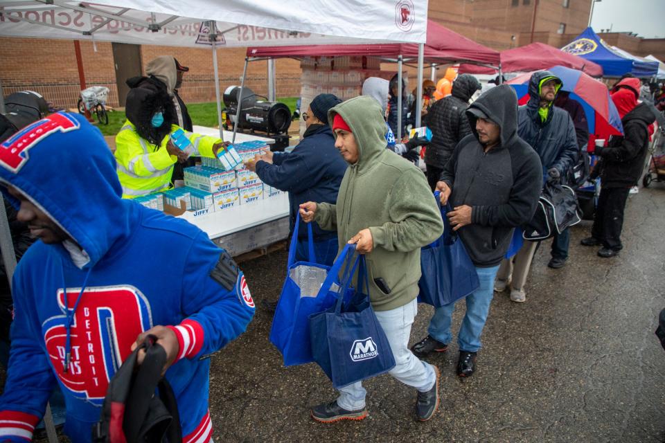 Marcelino Manciles Landa, 36, of Detroit collects food and a turkey during the annual Thanksgiving All-Star Giveback at River Rouge High School in River Rouge, Mich. on Tuesday, Nov. 21, 2023.