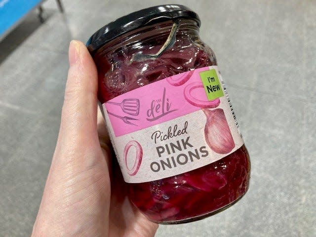 pickled pink onions in a jar in someone's hand at an aldi